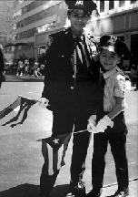 Black and white photo of two figures dressed in uniform, holding flags "Americanos: Latino Life in the United States"