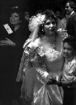 Black and white photo of a bride holding little boy with figures in the back, Americanos: Latino Life in the United States