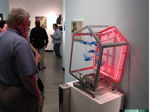 Person looking at bird cage sculpture with glowing red light