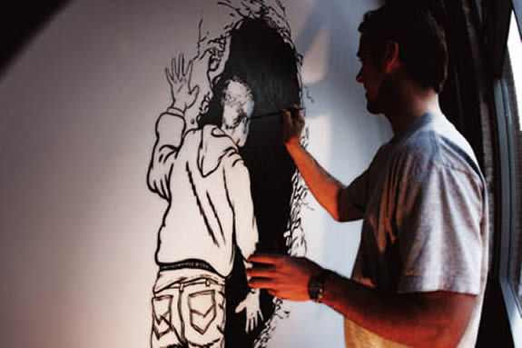 Man painting on a wall another man looking into a dark hole.