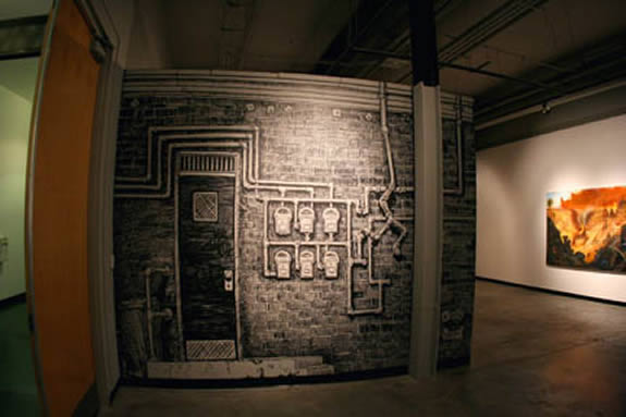 Gallery wall painted like the side of a building with electrical boxes and pipes.