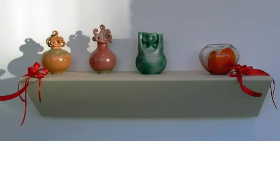 Four small vases on a shelf.