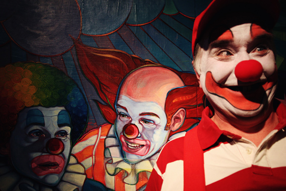 A clown standing in front of a clown painting