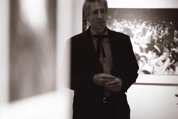 Man stands in the gallery space with bow-tie on.