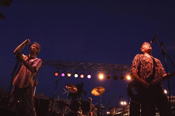 Band performing on a stage, two men in the foreground.