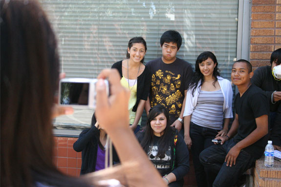 A woman photographing a group of teenagers.