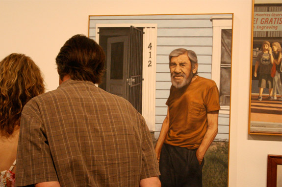 Two figures looking at artwork of of an old man in front of house
