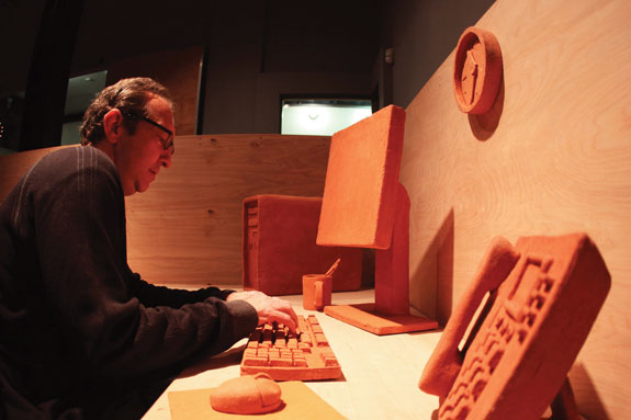 A man sitting in a clay sculpted office cubicle.