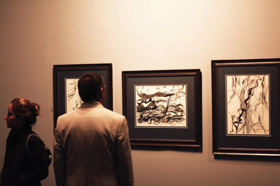 Two people looking at paintings from the Gokhman exhibition.