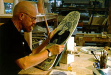Charles Krafft paints on a skateboard deck.