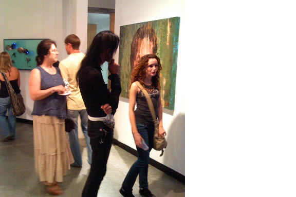 Visitors walking through a painting exhibit.