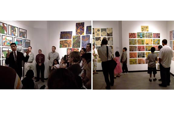 people fill a gallery space, artwork on the walls is colorful.