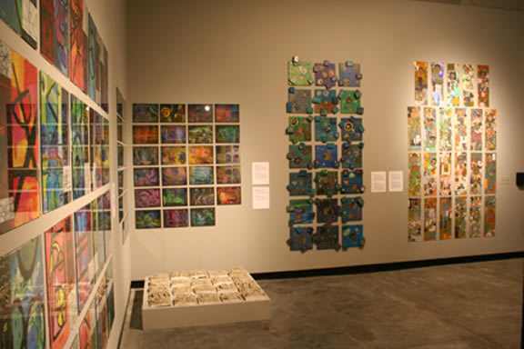 Installation image. White walls with rows of artwork hung.