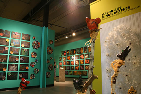 Installation of gallery with colorful artwork filling the walls.