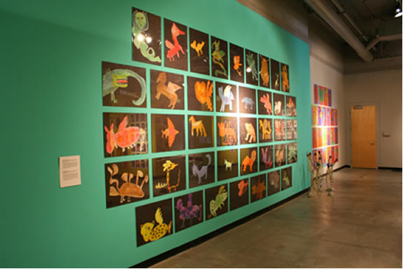 Gallery wall painting teal with square artworks coving them.
