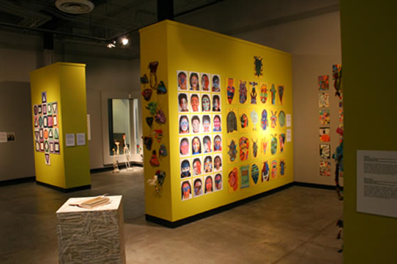 Gallery walls painted yellow with small artworks covering them.