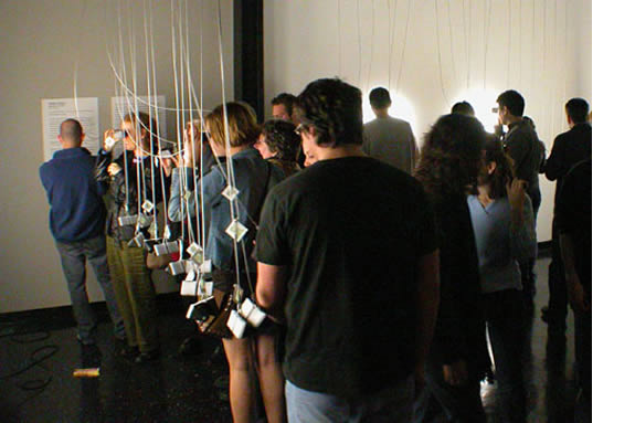 People in a line with hanging cubes to the left.