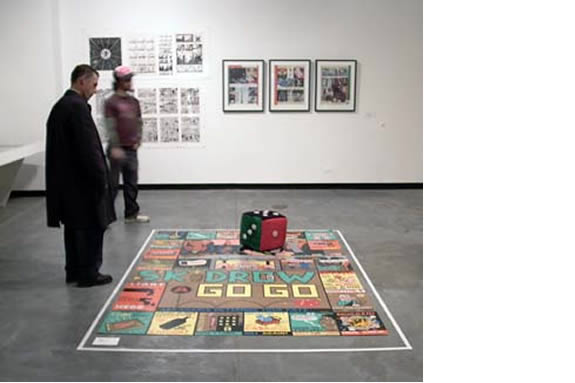 two people in a gallery space looking at artwork on the floor.