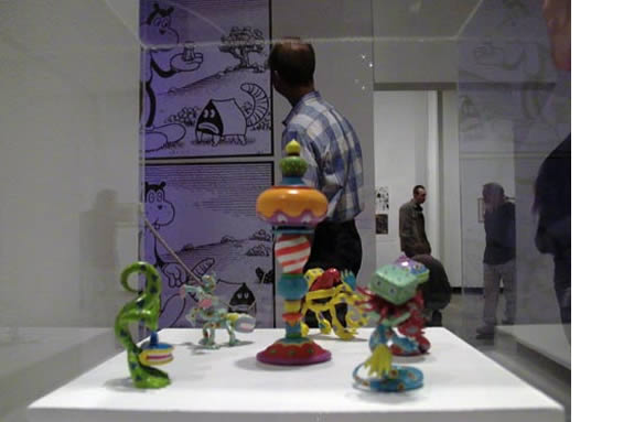 man looking at cartoon style artwork with figurines in the foreground.