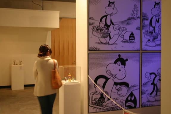 Woman in gallery looking at a cartoon style artwork.