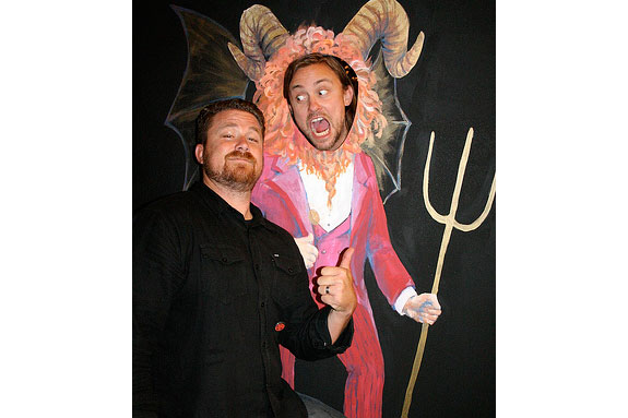 Two men posing at a Satan photo prop.