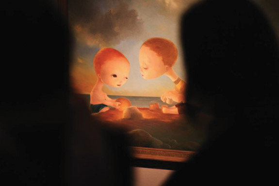 people stand in front of a painting of two boys on the beach
