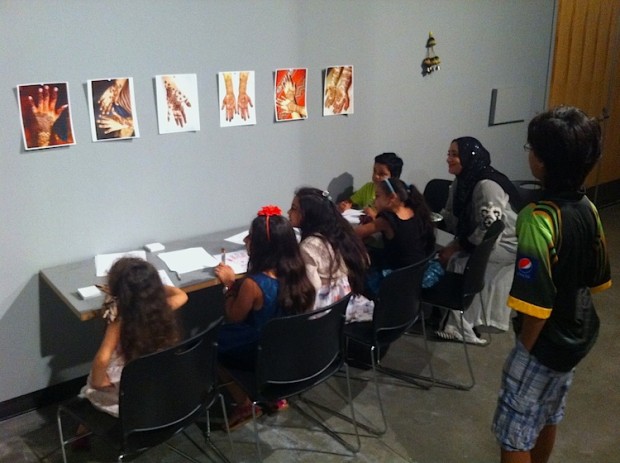 Children sitting at a table and looking at drawings of Henna