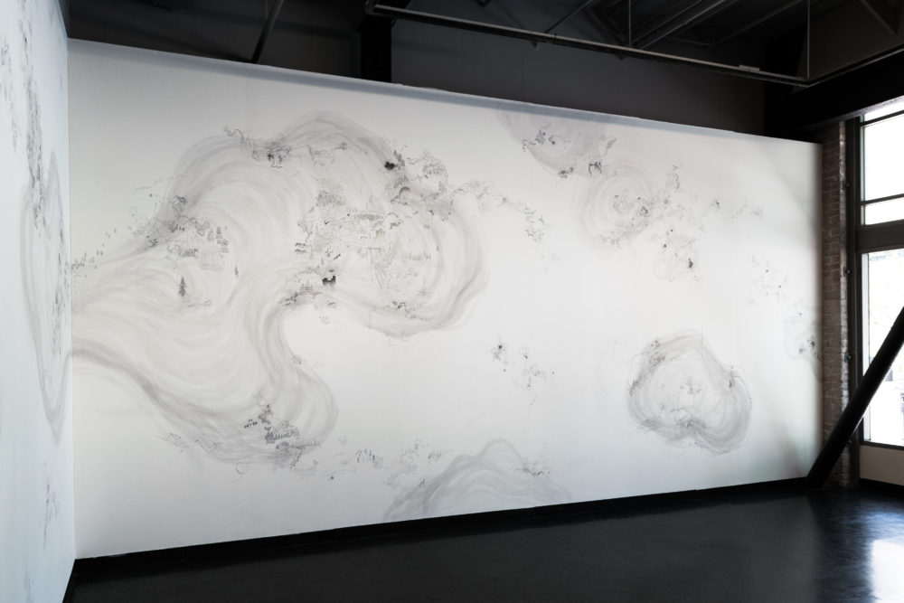 The mural is predominantly white, with intricate, almost microscopic details drawn in shades of gray.