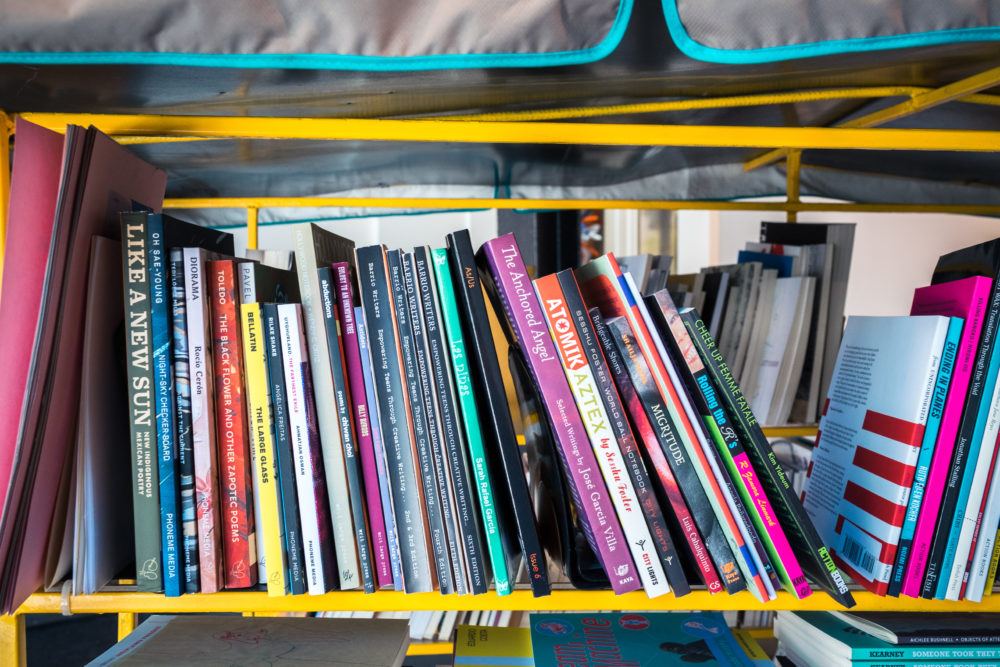 A metal shelving unit is filled with a variety of books, many of which are brightly colored or have eye-catching covers.