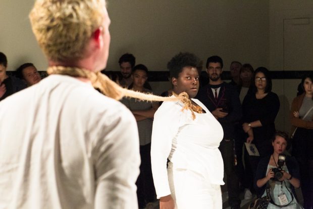 Artist Kenyatta Hinkle and Tyer Oyer performing in full white outfits tied to each other with role around their necks