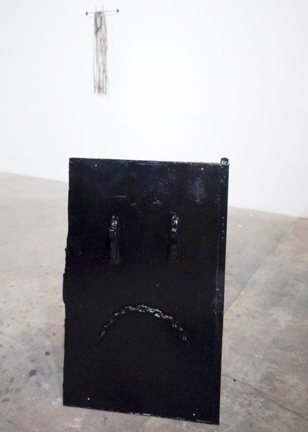 ":(" by Eric Sick consisting of drywall, metal chain, wooden hooks, paint, cinderblock