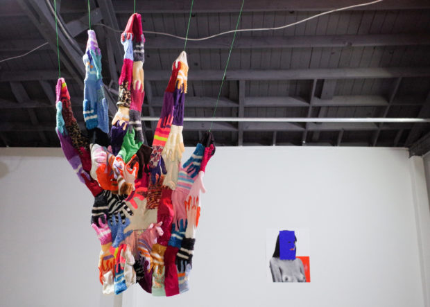 "No Glove No Love" fabric sculpture made of gloves by Lana Licata with "I Thought California Would Be Different..." print by Esteban Schimpf in the background.