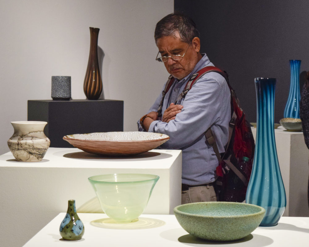 OLDER MAN LOOKING AT CERAMIC PLATTER