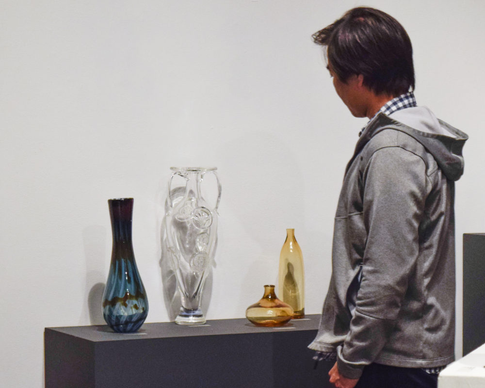 YOUNG MAN LOOKING AT GLASS VASE