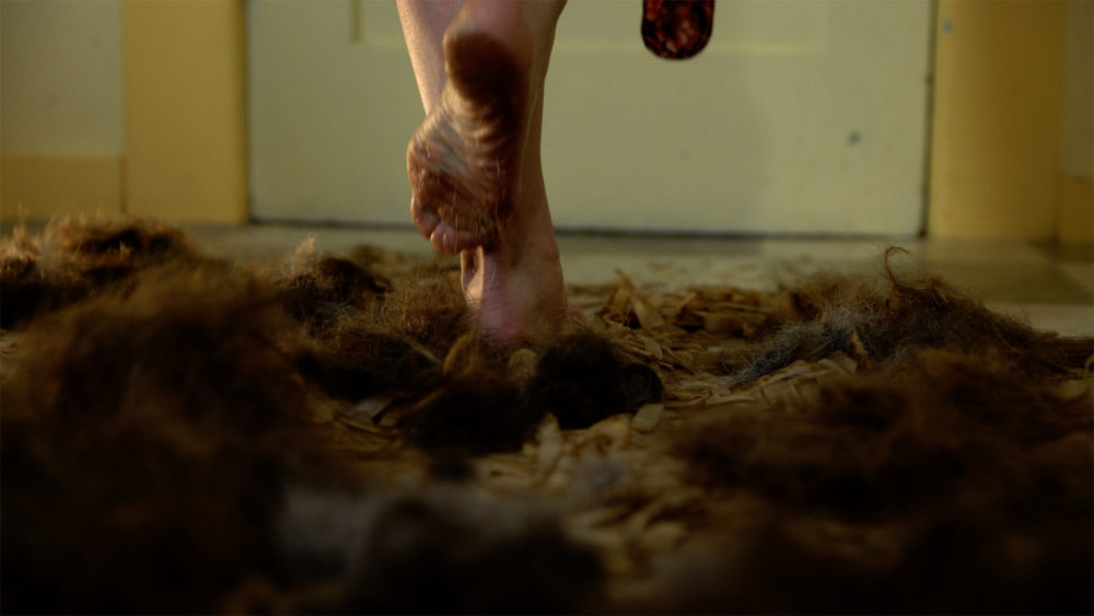 A pair of bare feet standing in a pile of hair