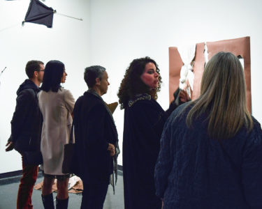 Artists talking with visitors in front of work