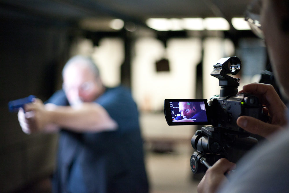 Individual filming a person shooting a gun