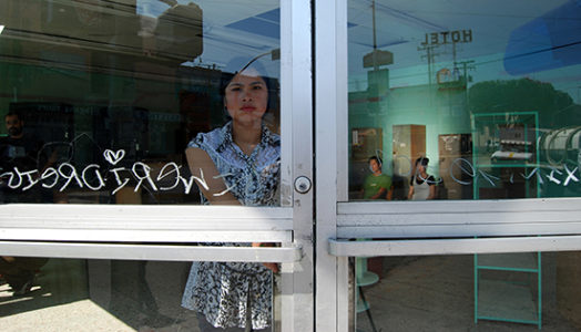 Woman looking at the viewer through glass doors with tagging upon them