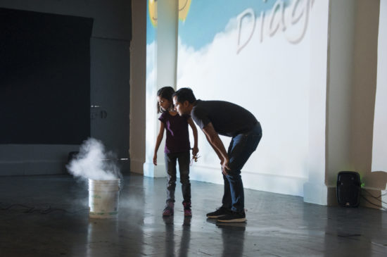 Man and young girl looking at bucket with fog coming out