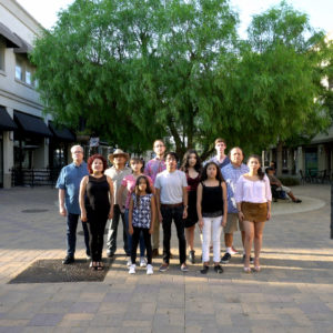 Group of twelve individuals standing together side by side on a plaza