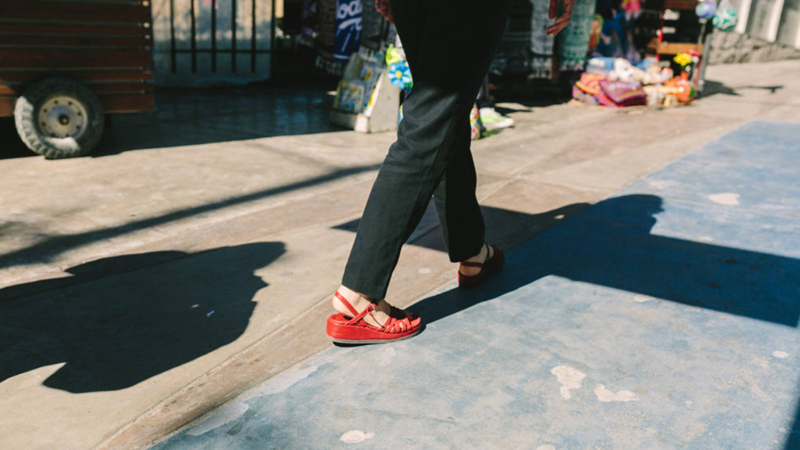 Red shoes walking on the sidewalk.