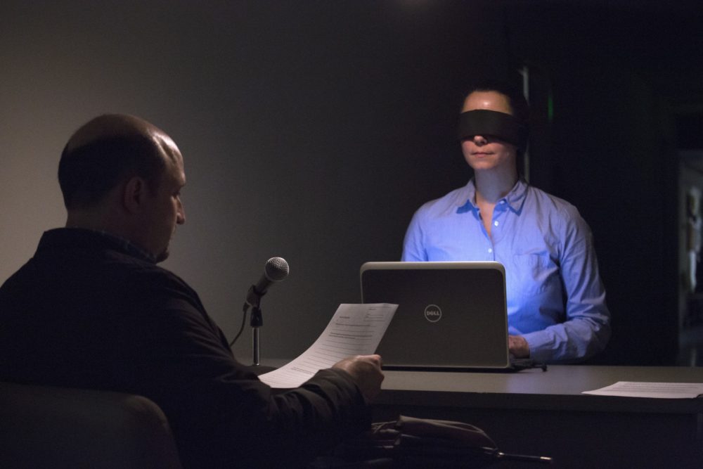 Man sitting in front of woman in blindfold.