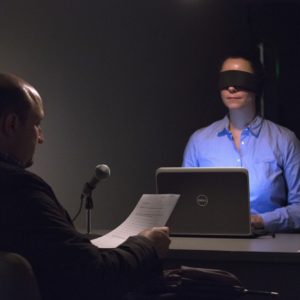 Man sitting in front of woman in blindfold.