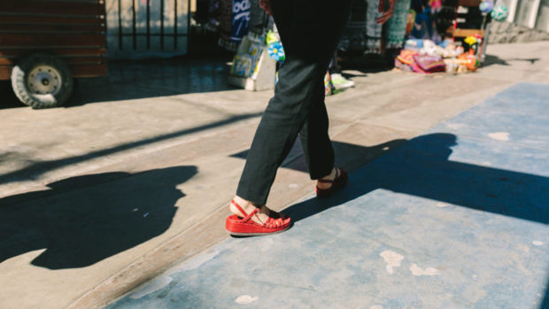 An individual walking wearing red wedges