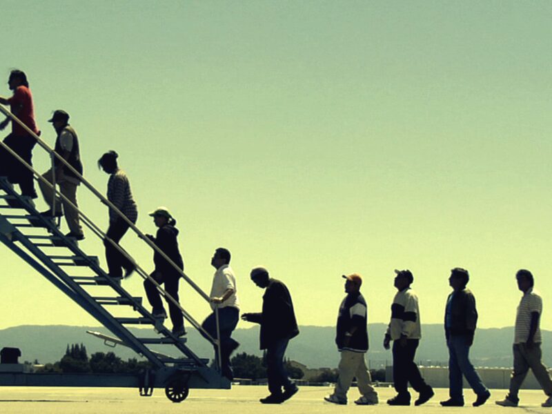 Individuals in a line climbing an airplane entry staircase