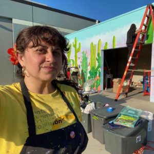 artist Alicia Rojas standing in front of an in progress mural