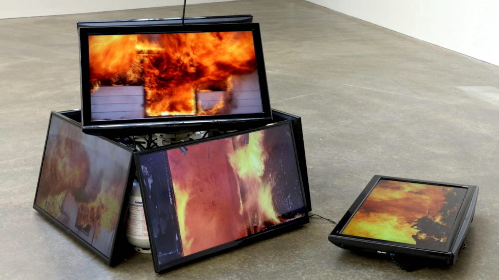 video monitors started upon one another with images of fire on screen.
