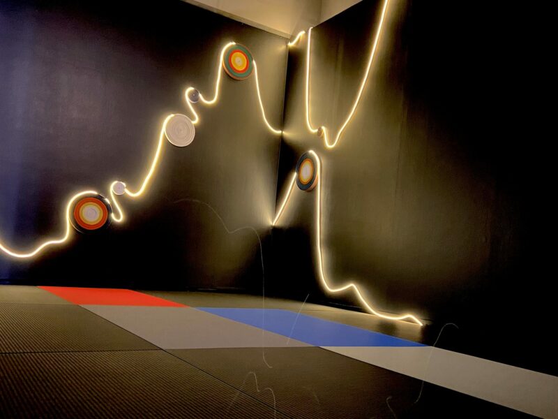 squiggly white light installation against black wall