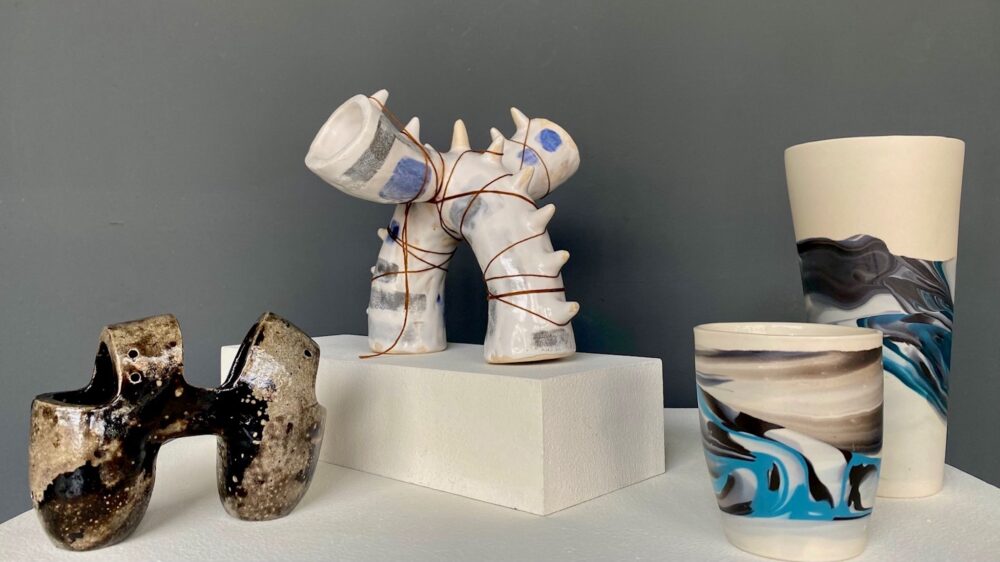 four works of ceramics on display. two to the left more abstract objects, two to the right more vase shaped.