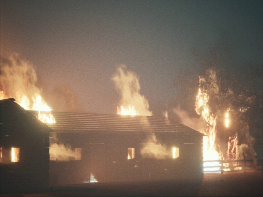 Image of a house like building on fire at night time.